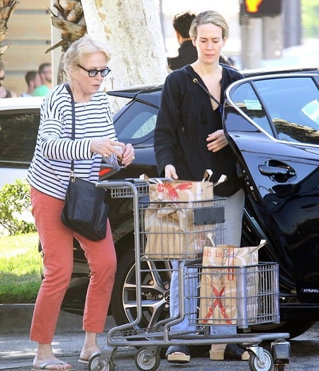 A picture of Holland Taylor and her partner Sarah Paulson putting their groceries in their black Mercedes.